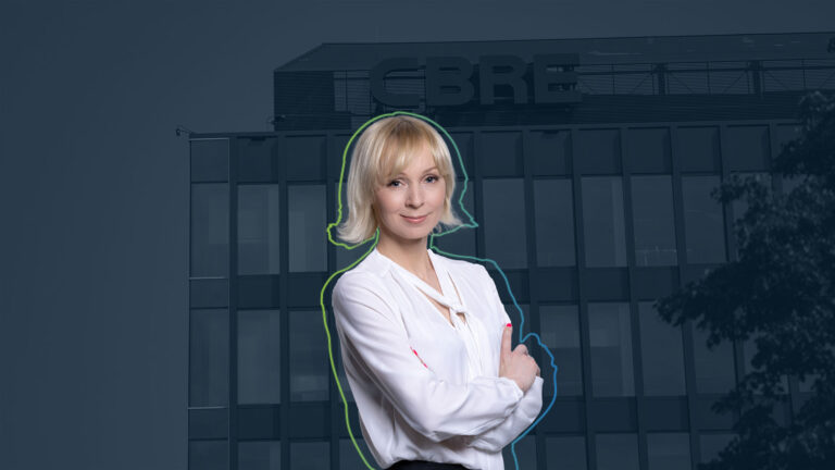 Portrait of Malgorzata Czepel, Director Industrial & Logistics at CBRE Poland with crossed arms in front of an office building with the lettering 'CBRE'