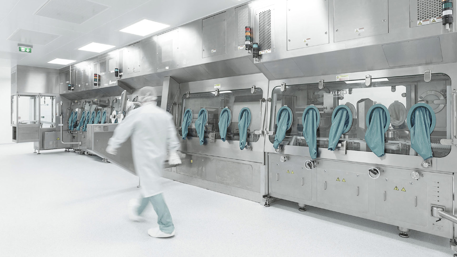 Reinraum mit großer Maschine mit mehreren blauen Handschuhen und Person in Schutzkleidung