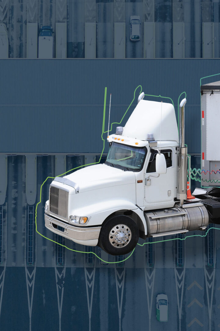 Image for system selection on the subject of TMS consulting, showing a large goods transporter in the foreground and a logistics center or distribution center in the background.